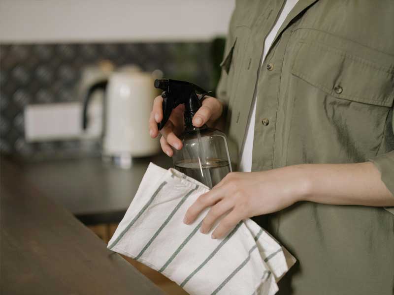 A Lenuma cleaner holding a reusable spray bottle and cloth, representing eco-friendly and attentive home care in North Vancouver.
